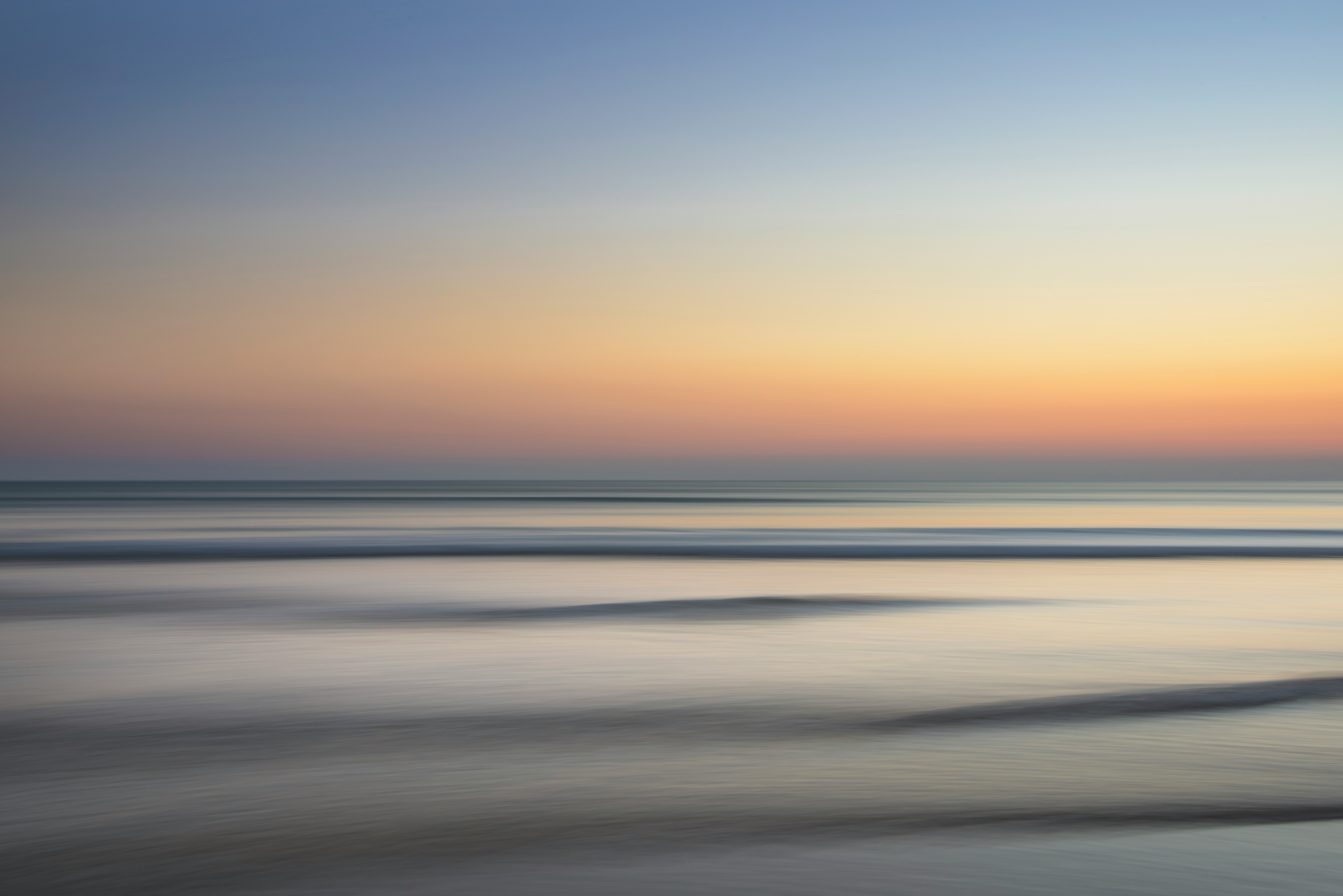 Calm ocean meeting a soft, glowing sky at dusk